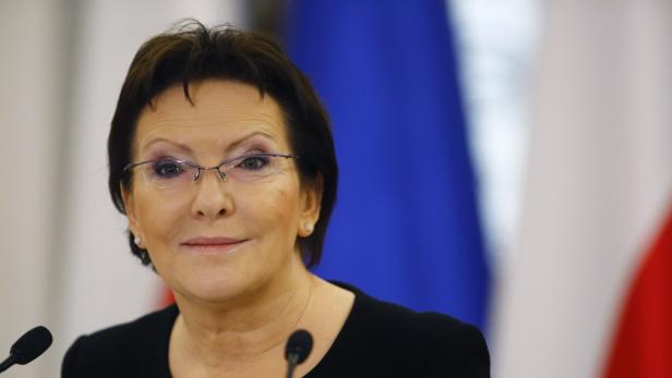 Eine Frau mit Brille steht vor Flaggen.