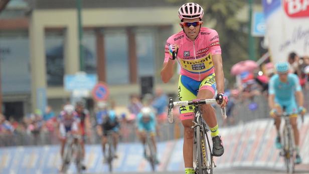 Ein Radrennfahrer im rosa Trikot feiert seinen Sieg.
