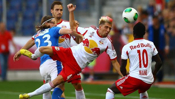 Ein Fußballspieler von Red Bull Salzburg versucht, den Ball zu spielen, während er von Gegenspielern umgeben ist.
