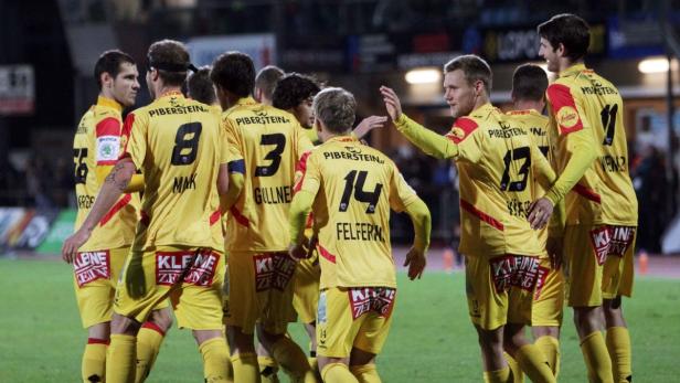 Eine Gruppe von Fußballspielern in gelben Trikots umarmt sich auf dem Spielfeld.