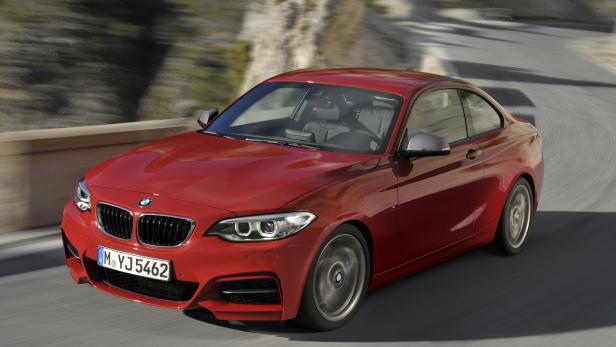 Ein roter BMW der 2er-Reihe fährt auf einer kurvigen Straße.