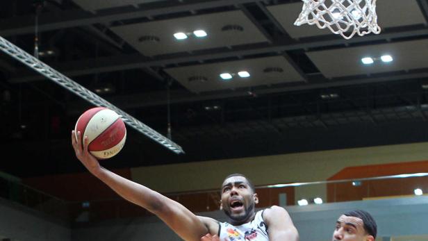Ein Basketballspieler wirft den Ball in Richtung Korb.