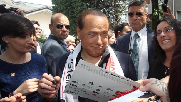 Silvio Berlusconi signiert ein Dokument mit dem Logo des AC Mailand.