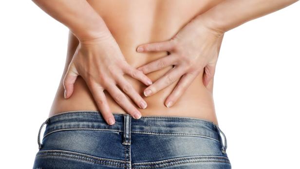 Eine Frau in Jeans hält sich den unteren Rücken.