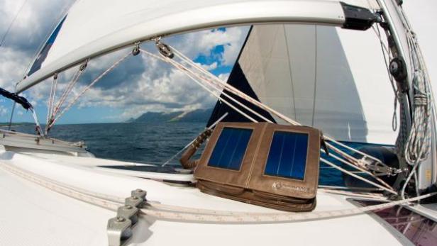 Ein Solarladegerät liegt auf dem Deck eines Segelboots auf dem offenen Meer.
