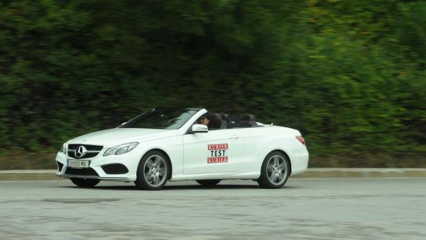 Ein weißes Mercedes-Benz Cabriolet fährt auf einer Straße.