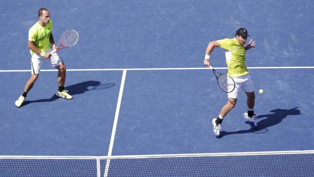 Zwei Tennisspieler auf einem blauen Tennisplatz während eines Matches.