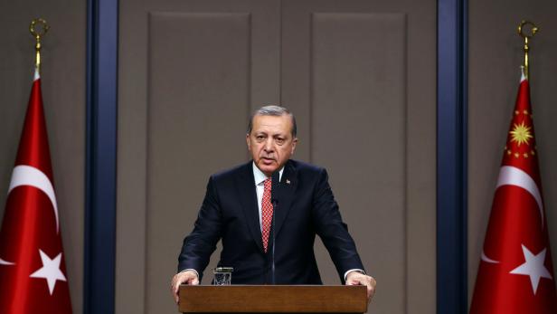 Recep Tayyip Erdoğan hält eine Rede vor türkischen Flaggen.