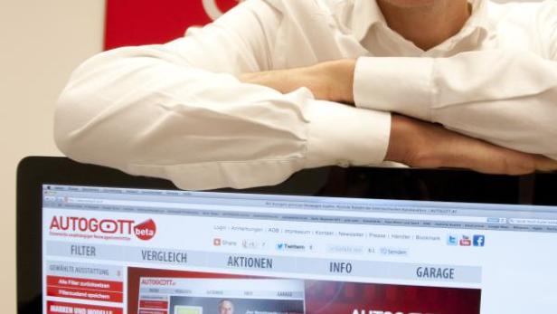 Ein Mann lehnt an einem Bildschirm, der die Website Autogott.at zeigt.