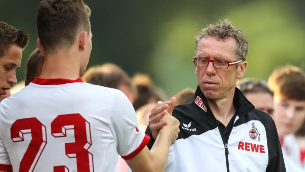 Ein Fußballspieler gibt dem Trainer des 1. FC Köln die Hand.