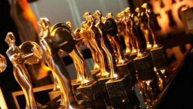 Viele goldene Statuetten stehen aufgereiht auf einem Tisch.