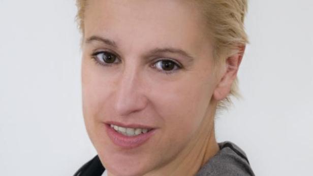 Eine Frau mit blonden, kurz geschnittenen Haaren lächelt in die Kamera.