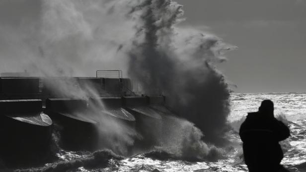 A man watches stormy seas in strong winds as waves