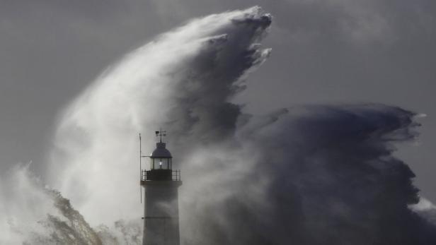 Eine riesige Welle bricht an einem Leuchtturm.