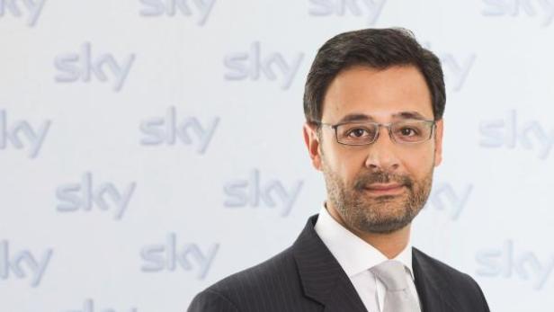 Ein Mann mit Brille und Anzug vor einem Hintergrund mit dem „Sky“-Logo.