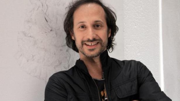 Ein Mann mit Bart und dunkler Jacke lächelt in die Kamera.