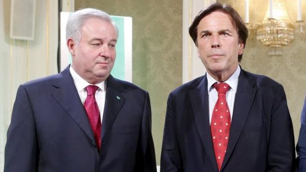 Zwei Männer in Anzügen stehen nebeneinander.