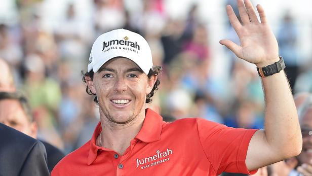 Rory McIlroy mit Kappe und rotem Hemd winkt in die Menge.