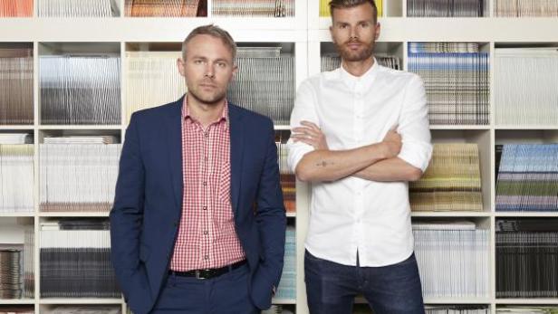 Zwei Männer posieren vor einem Regal voller Schallplatten.