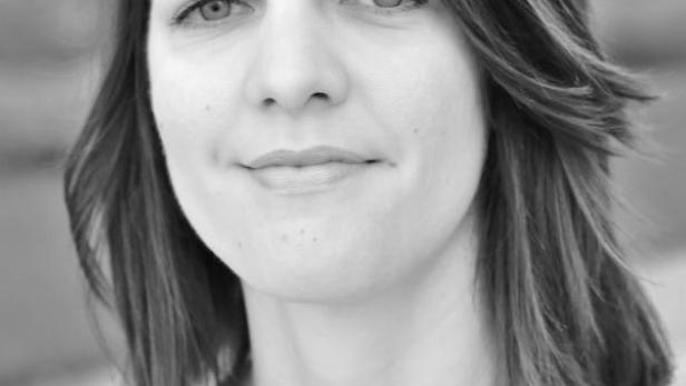 Porträt einer Frau mit schulterlangem, gewelltem Haar.