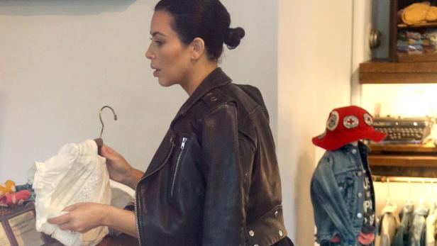 Kim Kardashian betrachtet ein weißes Kleidungsstück in einem Bekleidungsgeschäft.