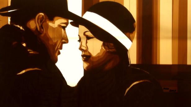 Ein Mann mit Hut und eine Frau mit Hut schauen sich an.