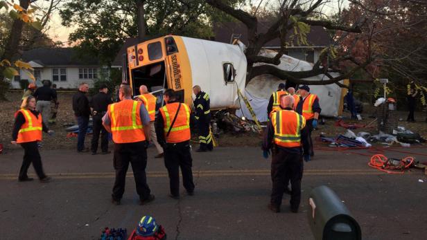 Ein Schulbus liegt nach einem Unfall auf der Seite, umringt von Rettungskräften.