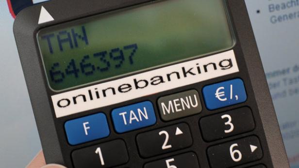 Eine Frau führt mit einem TAN-Generator und ihrer Bankcard eine Überweisung per Onlinebanking durch (Symbolbild)