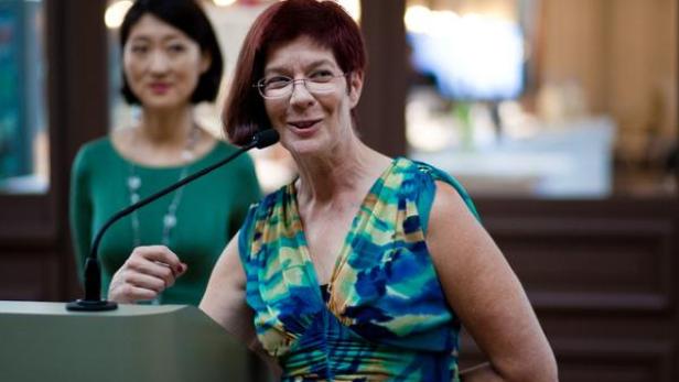 Eine Frau mit Brille spricht an einem Rednerpult vor Publikum.
