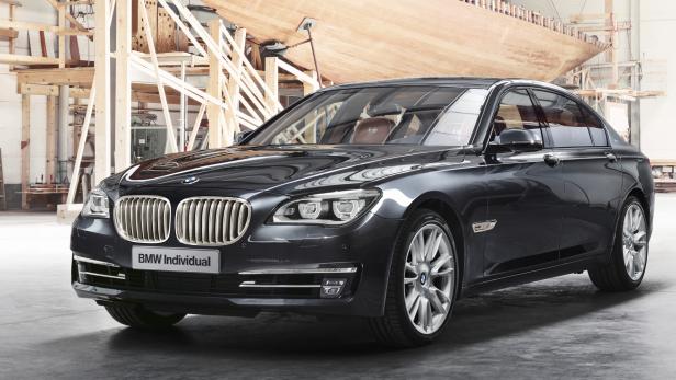 Ein schwarzer BMW Individual steht in einer Werkstatt vor einem Holzboot.