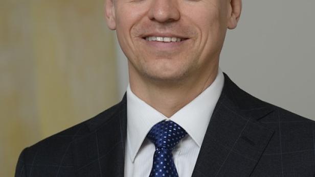 Ein Mann mit Anzug und Krawatte lächelt in die Kamera.