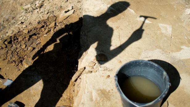 Der Schatten einer Person hält einen Hammer neben einem Eimer Wasser.