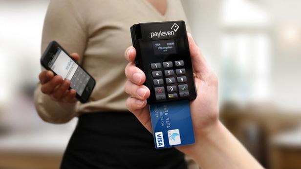 Eine Person bezahlt mit einer Visa-Karte über ein mobiles Payleven-Terminal, während eine andere Person ein Smartphone hält.