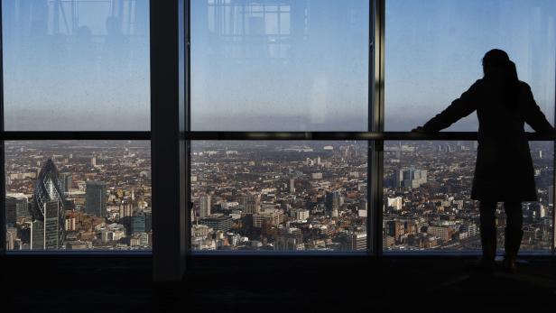 A woman looks over the financial district from a window in The View gallery at the Shard, western Europe&#039;s tallest building, in London January 9, 2013. The View, the public viewing deck accessible by high speed elevators on the 309 metre (1,013 feet) Shard building, opens on February 1. Picture taken January 9, 2013. REUTERS/Luke Macgregor (BRITAIN - Tags: TRAVEL CITYSCAPE)