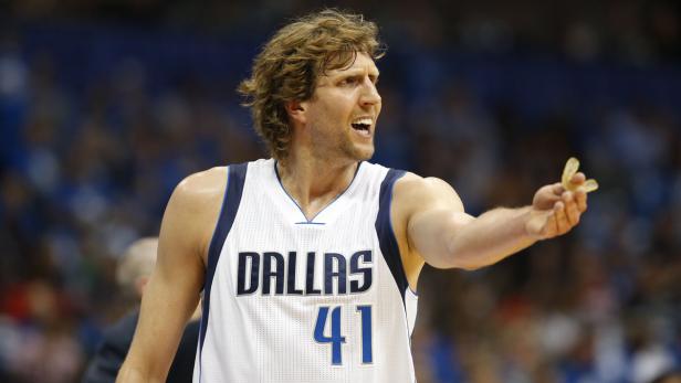 Dirk Nowitzki im Trikot der Dallas Mavericks mit einem Mundschutz in der Hand.