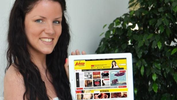 Eine junge Frau hält ein Tablet mit der Webseite von Antenne Vorarlberg in die Kamera.
