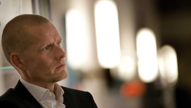 Ein Mann mit Anzug blickt nachdenklich zur Seite.