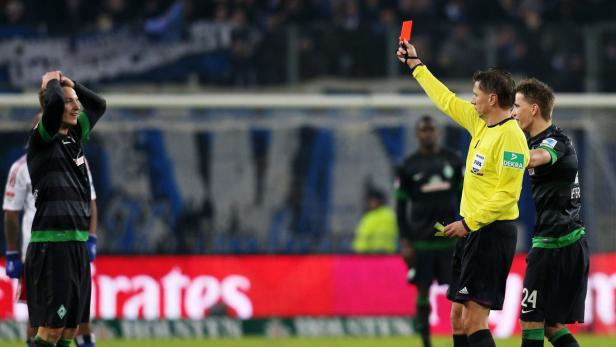 Ein Fußballschiedsrichter zeigt einem Spieler die Rote Karte.