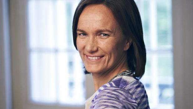 Eine Frau mit braunen Haaren lächelt in die Kamera.