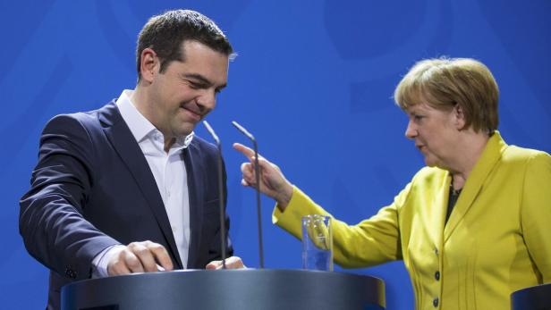 Angela Merkel gestikuliert neben Alexis Tsipras an einem Rednerpult.