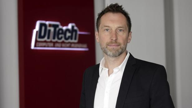 Ein Mann in einem Anzug steht vor dem DiTech-Logo.