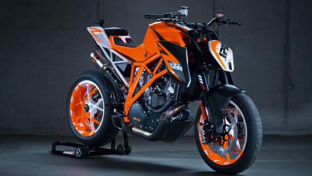 Ein orangefarbenes KTM Motorrad steht in einem Studio.