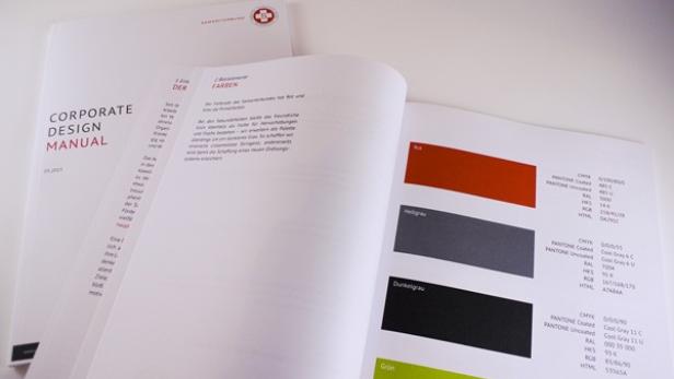 Ein geöffnetes Handbuch für Corporate Design zeigt Farbschemata und Richtlinien.
