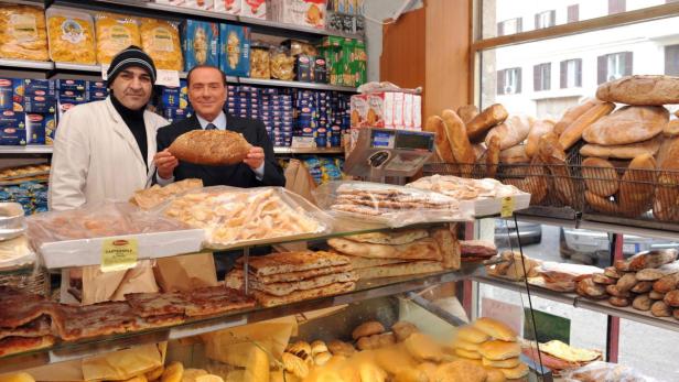 Silvio Berlusconi hält ein Brot in einem italienischen Lebensmittelgeschäft.