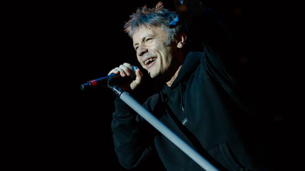 Bruce Dickinson von Iron Maiden singt auf der Bühne und macht eine Geste.