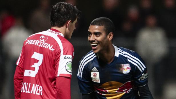 Ein lächelnder Fußballspieler im Gespräch mit einem Gegenspieler.