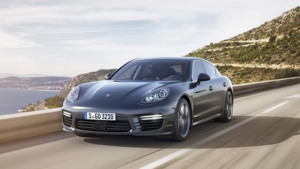 Ein grauer Porsche Panamera fährt auf einer Küstenstraße.