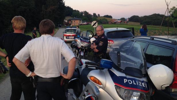 Polizisten und Zivilisten stehen an einem Tatort, im Hintergrund sind Polizeihubschrauber zu sehen.
