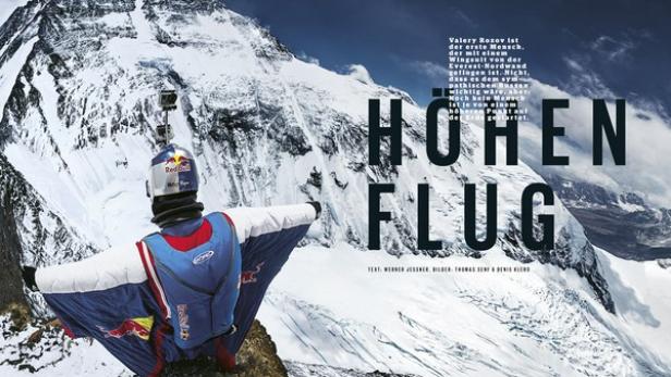 Ein Wingsuit-Pilot steht vor einer schneebedeckten Berglandschaft bereit zum Absprung.