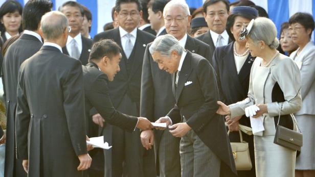 Der japanische Kaiser Akihito nimmt eine Nachricht von einem Beamten entgegen.